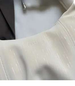 Macro shot of off-white pleated fabric texture with star-shimmer and logo embossing