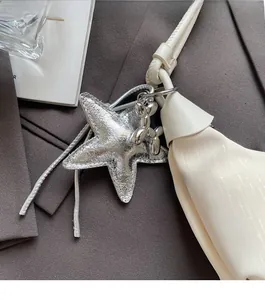 Detail of silver star charm and mini balloon dog pendant on white leather shoulder bag strap