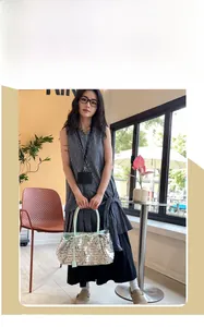 Detailed shot of silver sequined tote bag with mint green leather handles and straps
