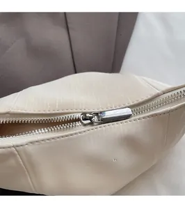 Detail of beige pleated shoulder bag featuring smooth silver zipper and textured PU leather
