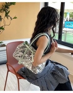 Detail of silver sequined tote bag with light green straps for a chic shiny texture