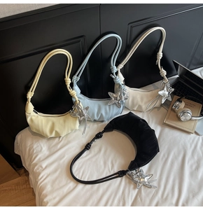Detailed view of four pleated crescent bags with star pendants and knotted shoulder straps