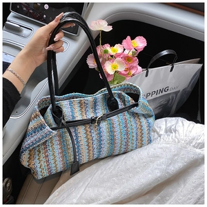 Detail shot of a rainbow woven tote bag featuring a chevron pattern and black leather handles