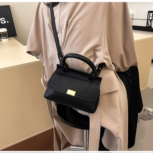 Dettaglio borsa nera in pelle a grana di litchi con elegante chiusura dorata quadrata