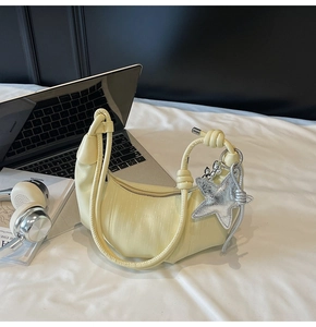 Detail of light yellow pleated dumpling bag with knot handle and silver star charm