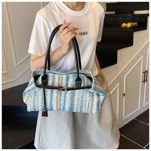 Detail of colorful woven tote bag featuring wavy patterns and black leather handles