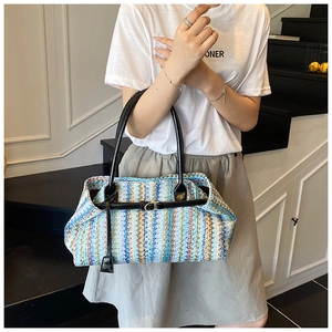 Detail of woven tote bag featuring blue chevron pattern and black leather handles