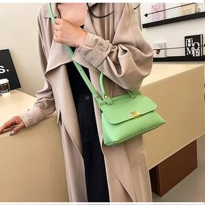 Dettaglio borsa verde brillante con trama litchi e fibbia dorata indossata da modella
