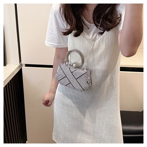 Detail of silver rhinestone clutch with pearl clasp and woven metal handle for formal wear