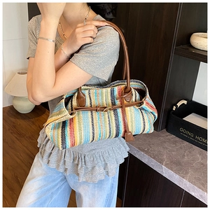 Detail of colorful striped woven tote bag with brown leather handles and buckle closure