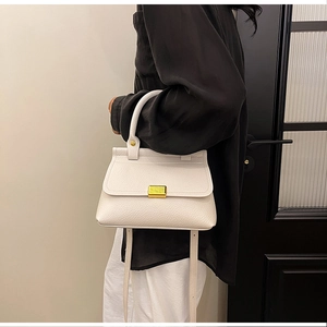 Dettaglio di una borsa a mano bianca in pelle martellata con chiusura in metallo oro