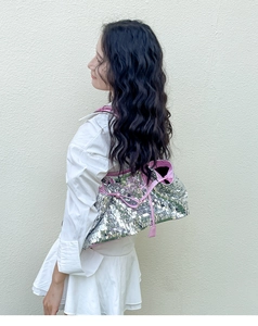 Silver sequin shoulder bag with pink leather trim worn by a model in casual outfit