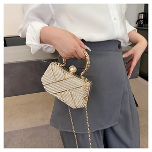 Detail of evening clutch bag with white pearls, gold geometric lines and top latch