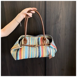 Close-up of colorful striped woven tote bag featuring deep brown leather handles