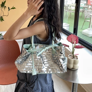 Detail of silver sequin tote bag with mint green handles and metallic texture finish