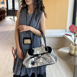 Detailed shot of silver sequin tote bag with black leather handles and metal buckle