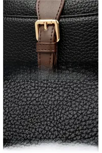 Detail of lychee pattern leather and adjustable brown strap buckle on black handbag