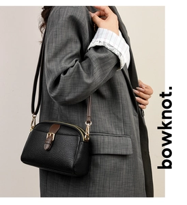 Close-up of black lychee leather crossbody bag with brown strap buckle on model's side