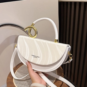 White half-moon handbag with wave texture and gold metal ring handle in a model's hand