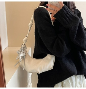Detailed shot of an off-white pleated crescent bag with a star charm and knotted strap