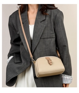 Detail of soft beige crossbody bag with pebble texture on grey striped blazer
