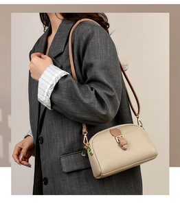 Close-up of beige lychee leather crossbody bag with brown trim and gold hardware