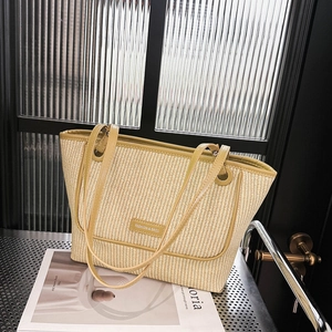Minimalist woven tote bag with green leather trim and fashion metal plaque on front