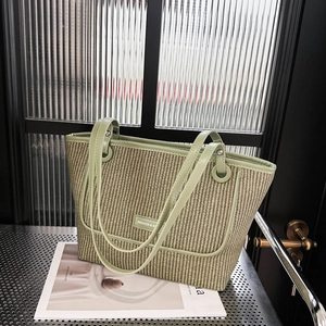 Minimalist green woven straw tote bag with leather handles and metallic logo detail