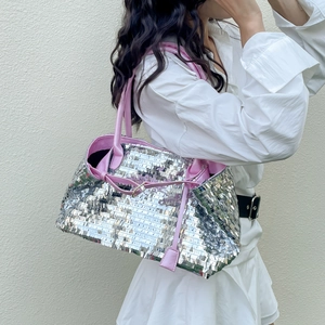 Detail of silver sequin tote bag with pink leather handles and metallic buckle decor