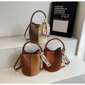 Three-tiered display of two-tone bucket bags featuring lychee grain leather and silk ribbon