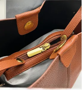 Detail of lychee pattern leather underarm bag featuring smooth gold zipper and magnetic snap