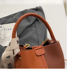 Detail of lychee pattern leather bucket bag with silk scarf wrapped around the handle