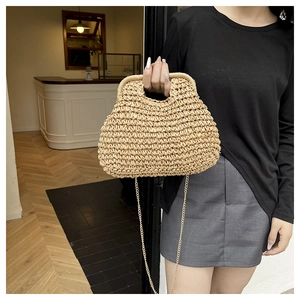 Detail of hand-woven straw handbag with chic gold metal chain strap in a cafe setting
