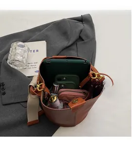 Litchi pattern bucket bag showing large interior capacity with iPad and smartphone