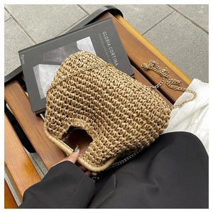 Detail of woven straw handbag featuring tight wavy texture and gold metal chain strap