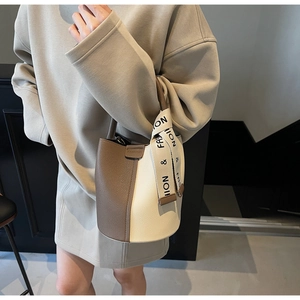 Close-up of contrast stitch bucket bag featuring lychee texture and fashion ribbon