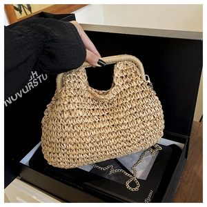 Detail of woven straw handbag in beige with sturdy top handle and gold chain strap