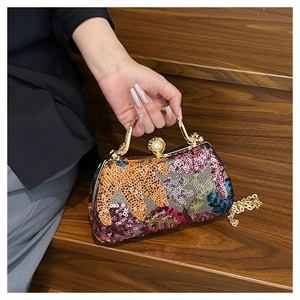 Close-up of sequin floral embroidery, pearl clasp, and gold chain on the evening bag