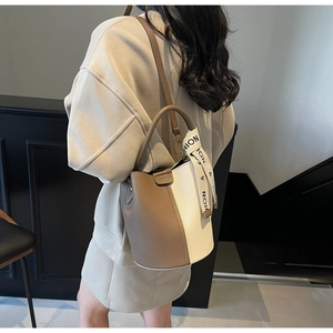 Detail of lychee pattern bucket bag with contrast stitching and decorative silk scarf strap