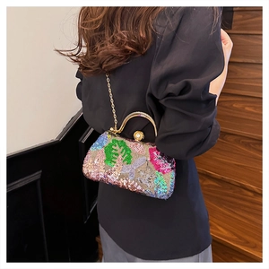 Detailed close-up of colorful floral sequins and golden handle with pearl clasp on handbag