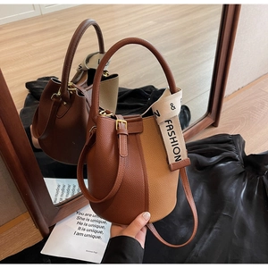 Close-up of litchi pattern leather detail and dual strap design on color-block bucket bag