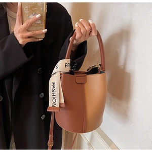 Close-up of contrast leather bucket bag with litchi texture and decorative scarf