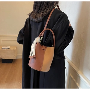 Detailed back view of a two-tone leather bucket bag with fashion scarf on a model