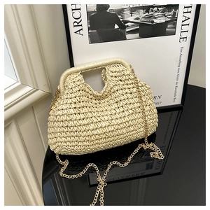 Close-up of cream woven handbag with gold chain strap on a black surface