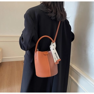 Caramel bucket bag detail with lychee texture and stylish decorative scarf on handle