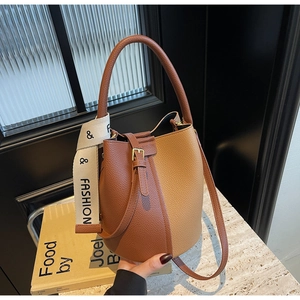 Detail of lychee textured leather bucket bag featuring a brown color-block design