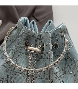Détail du sac seau en denim orné de strass brillants et d'un cordon de serrage argenté