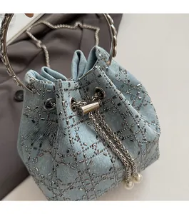 Détail du sac seau en denim avec motif cannage en strass et pompon en perles élégant