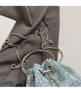 Détail du sac seau en denim bleu clair avec clous argentés et bandoulière en chaîne
