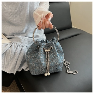 Détail du sac seau en denim avec cordon perlé et poignée en anneau métallique